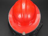 a red fireman ' s hat sitting on a black surface