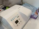 une machine blanche posée sur un comptoir, à côté d'un récipient bleu