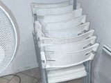 a white fan sitting next to a stack of white chairs