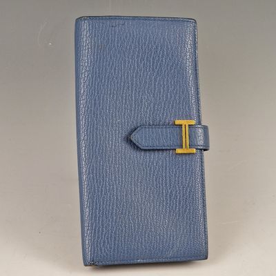 a blue leather wallet with a gold t on the front
