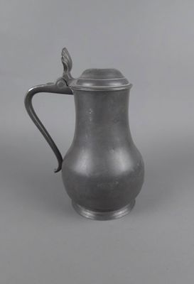 un pichet ancien en pewter muni d'une anse, sur fond gris