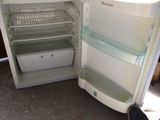 an open refrigerator with the door open and a person ' s feet resting on the floor