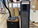 un purificateur d'air noir et doré à côté d'un autre purificateur d'air noir et doré, posé sur un parquet