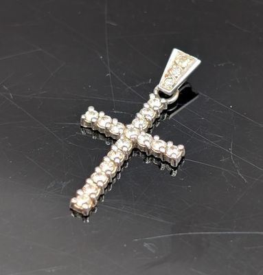 pendentif en forme de croix en argent orné de pierres blanches sur un fond noir
