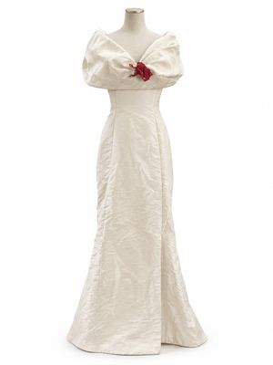 une robe blanche ornée d'une rose rouge sur l'épaule