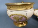 a gold and pink vase and a plate on a table