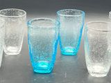 six glasses sitting on a table with a blue liquid in them