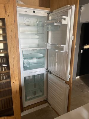 un réfrigérateur ouvert dans une cuisine, avec une cave à vin derrière