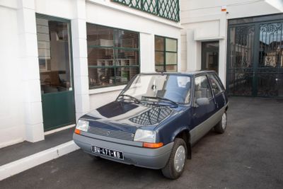 a small blue car parked in front of a building
