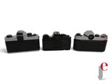 three black cameras sitting side by side on a white surface