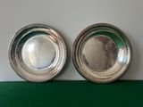 two silver plated dishes on a green surface