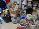 several buckets of paint and brushes sitting on a table in a room