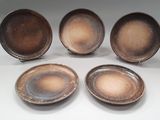 quatre assiettes marron posées les unes à côté des autres sur une surface blanche
