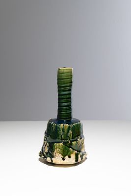 un vase vert sur lequel est posée une pile de pièces de monnaie