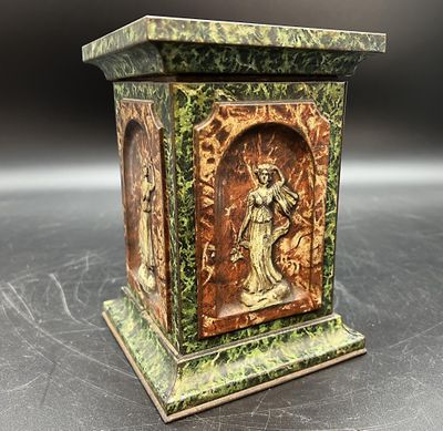 une statue représentant une femme, posée sur un socle posé sur une table