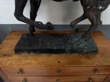 a bronze statue of a horse and a foal on a wooden table