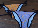 two bikinis with ties on them sitting on a wooden floor