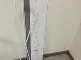 des toilettes situées dans un coin d'une pièce, équipées d'une brosse de toilettes et d'un distributeur de papier toilette