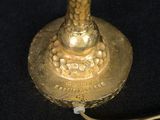 a gold table lamp that is on a black table
