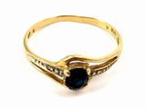 gros plan d'une bague en or avec une pierre bleue