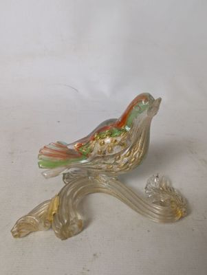 a glass bird that is sitting on a branch