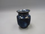 un vase bleu posé sur une table à fond blanc