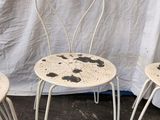two white chairs with black spots on them sitting next to a white curtain