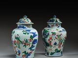 pair of chinese vases with painted figures on them on a table