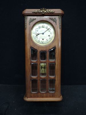 une horloge en bois exposée sur un fond noir