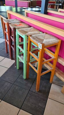brightly colored stools are lined up against a pink wall in a restaurant