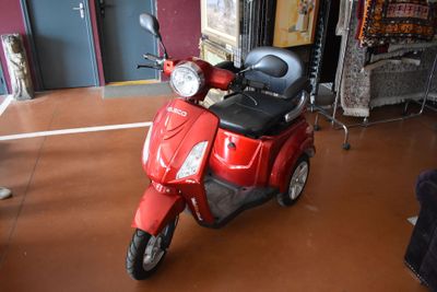 a red scooter that is parked in a room