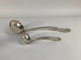 pair of silver spoons sitting on a white surface with a white background