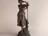 statue en bronze représentant une femme accompagnée d'un chien, posée sur un socle en marbre