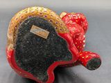 a red and gold elephant figurine sitting on a gray surface