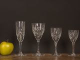 four empty wine glasses and an apple sit on a table