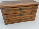 a small wooden chest with three drawers on top of it