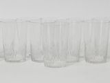 six clear glasses lined up in a row on a white surface