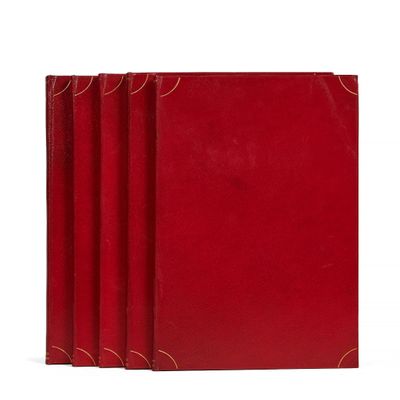 trois livres rouges superposés sur une surface blanche