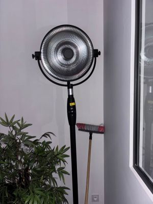 a fan that is on a stand next to a potted plant