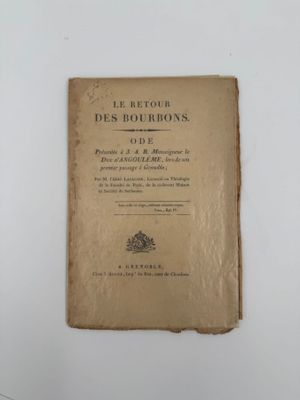 un vieux livre posé sur une table à côté d'un mur blanc