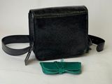 the small black purse with a bow tie is sitting on a white surface
