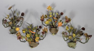 three wall sconces with flowers and leaves on them on a white surface
