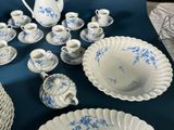 a blue and white table setting with a pitcher and cups and saucers