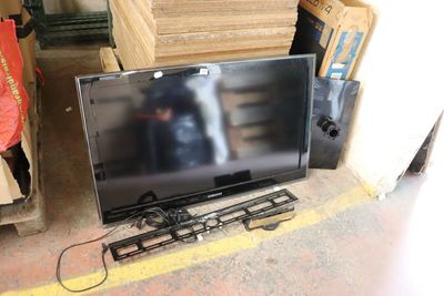 a flat screen tv sitting on the floor next to a pile of boxes
