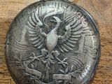 an old pocket watch with a bird on it sitting on a wooden table