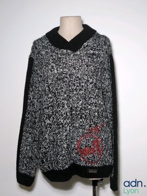 a black and white sweater with a red flower on it