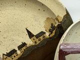 a plate with a picture of a town on it next to a plate with a picture of a town on it