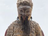 an old statue of a man with a beard sitting on a chair