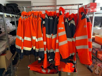 de nombreux gilets de sécurité orange suspendus à un porte-manteau dans une pièce