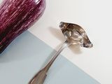 an eggplant next to a spoon on a blue and white surface